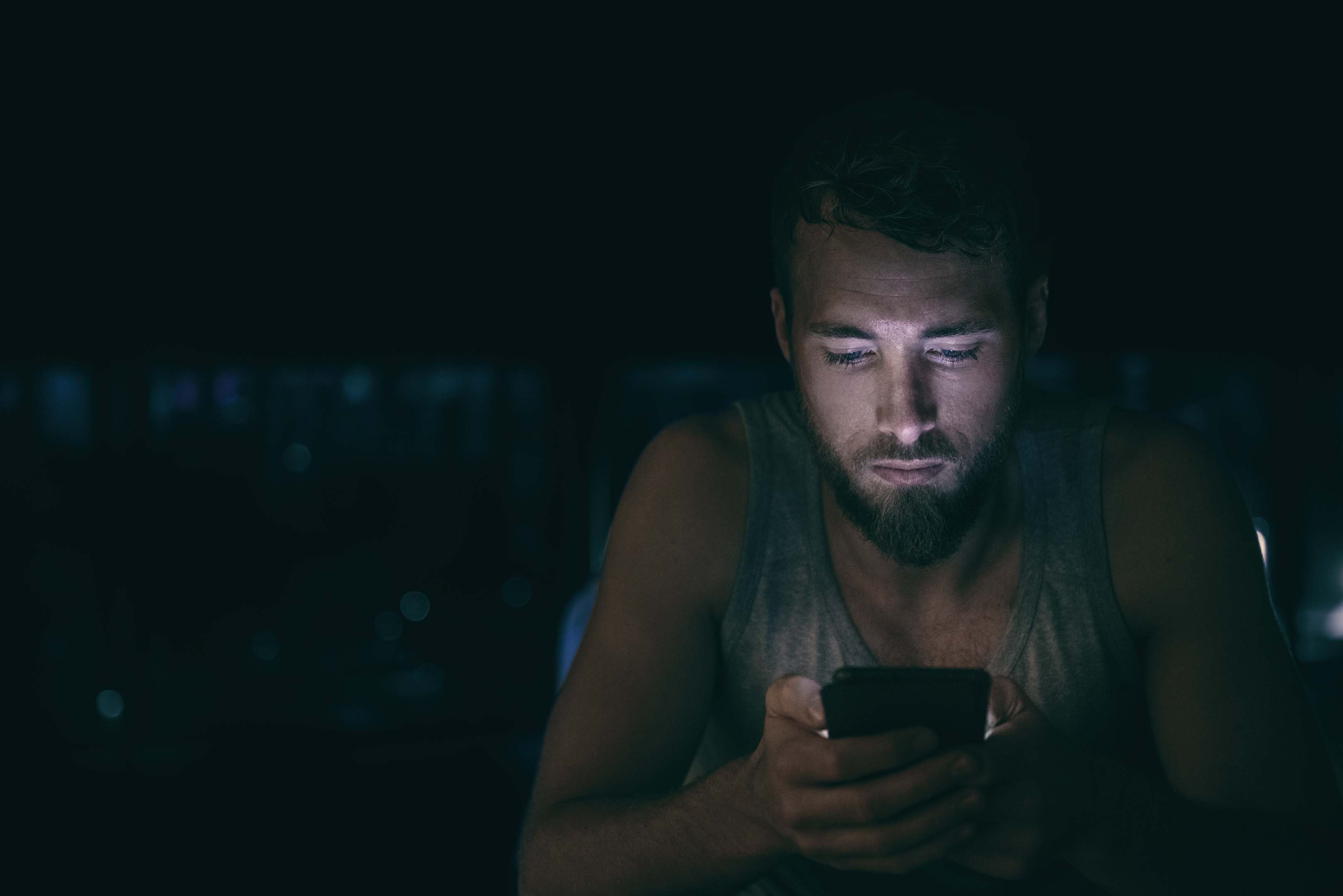 Person sitting in the dark looking at their smart phone