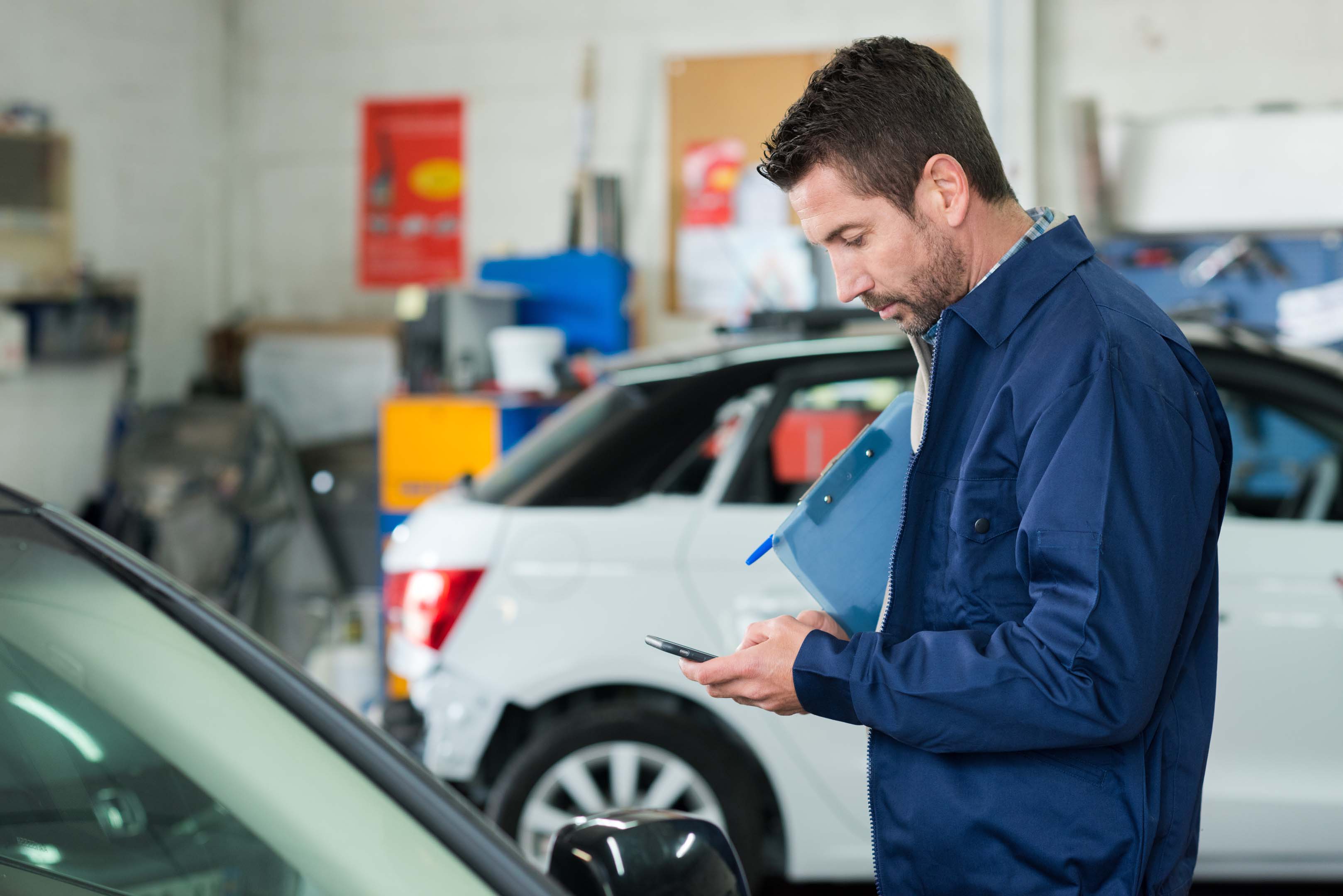 Garage technician searching for jobs on social media channels using a mobile phone