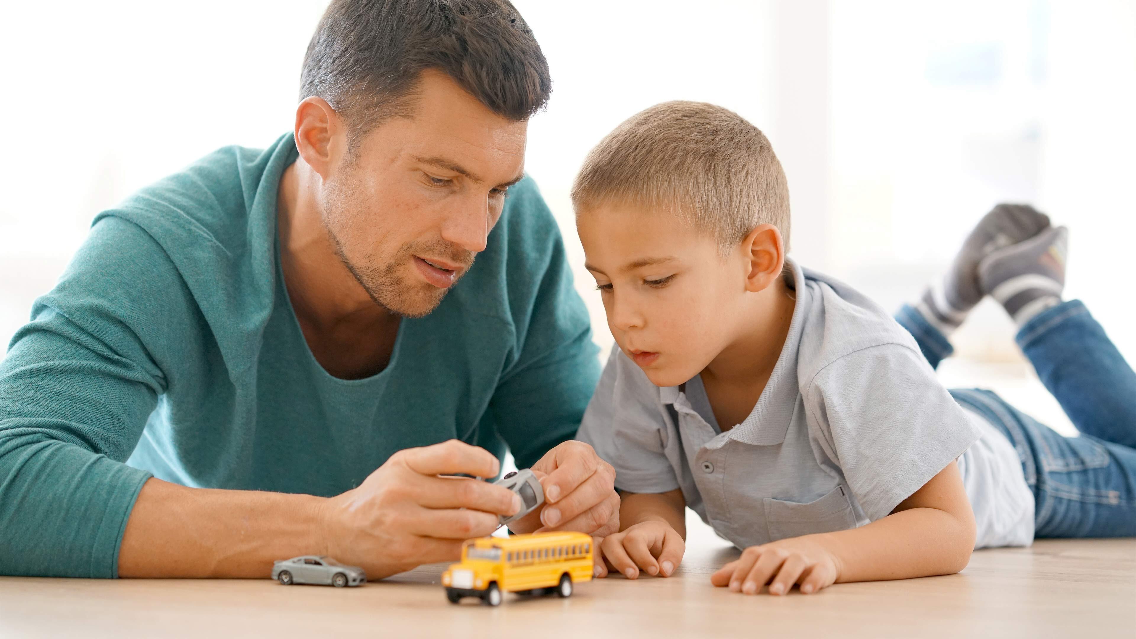 Father and son playing with cars together on the floor