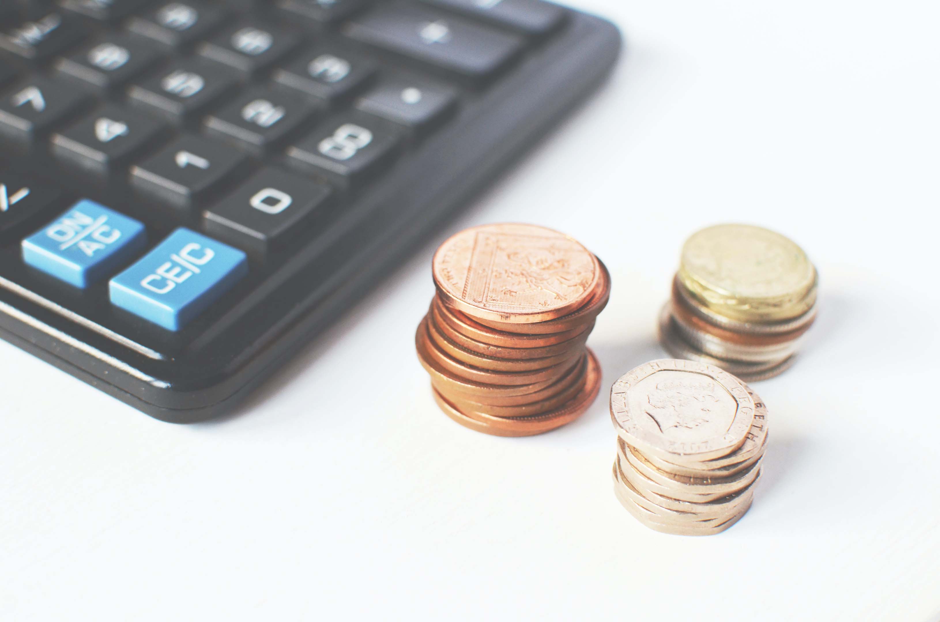 Three small piles of coins sitting next to a calculator