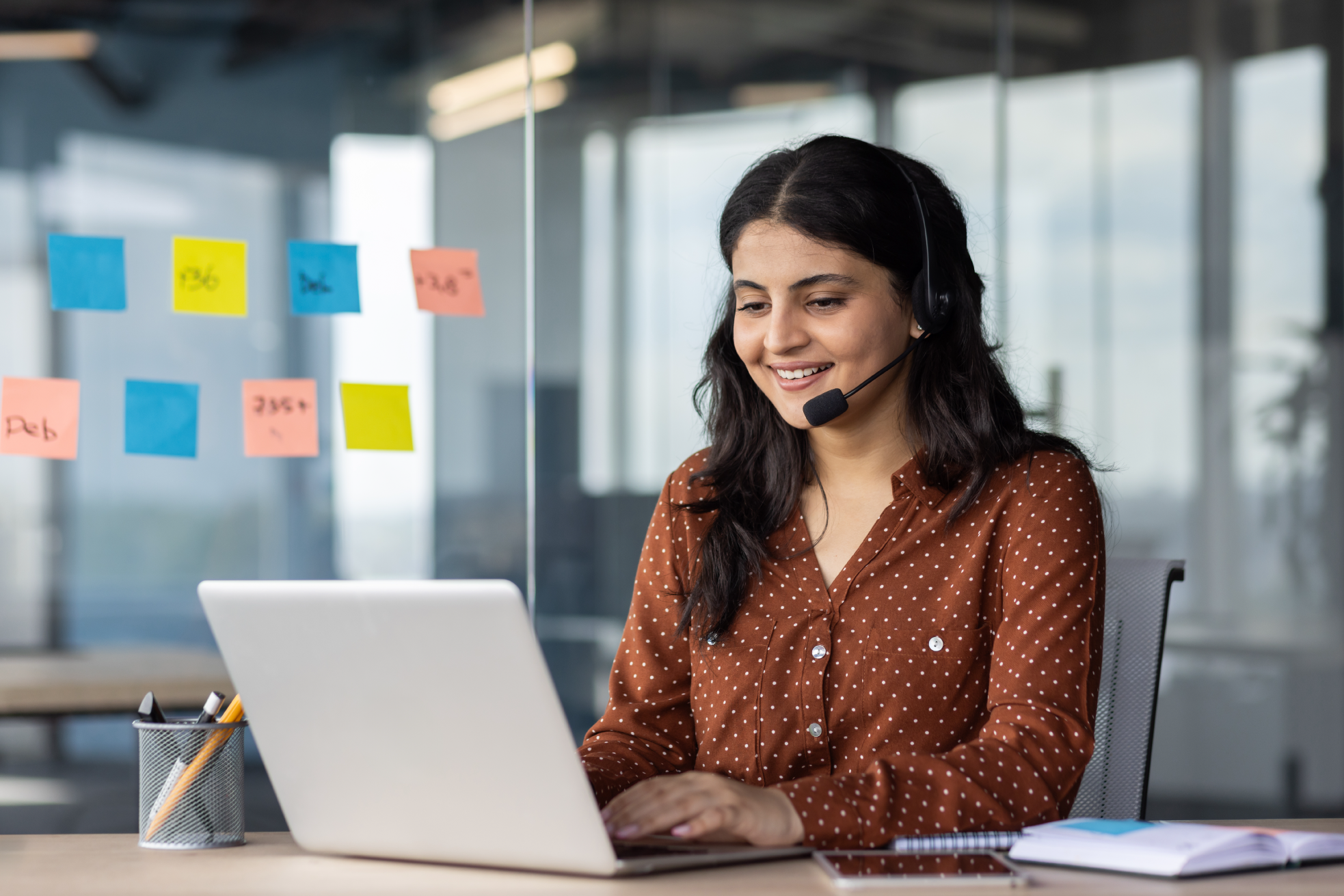 Online support worker at workplace, woman using headset phone for video call, business woman typing on computer keyboard.