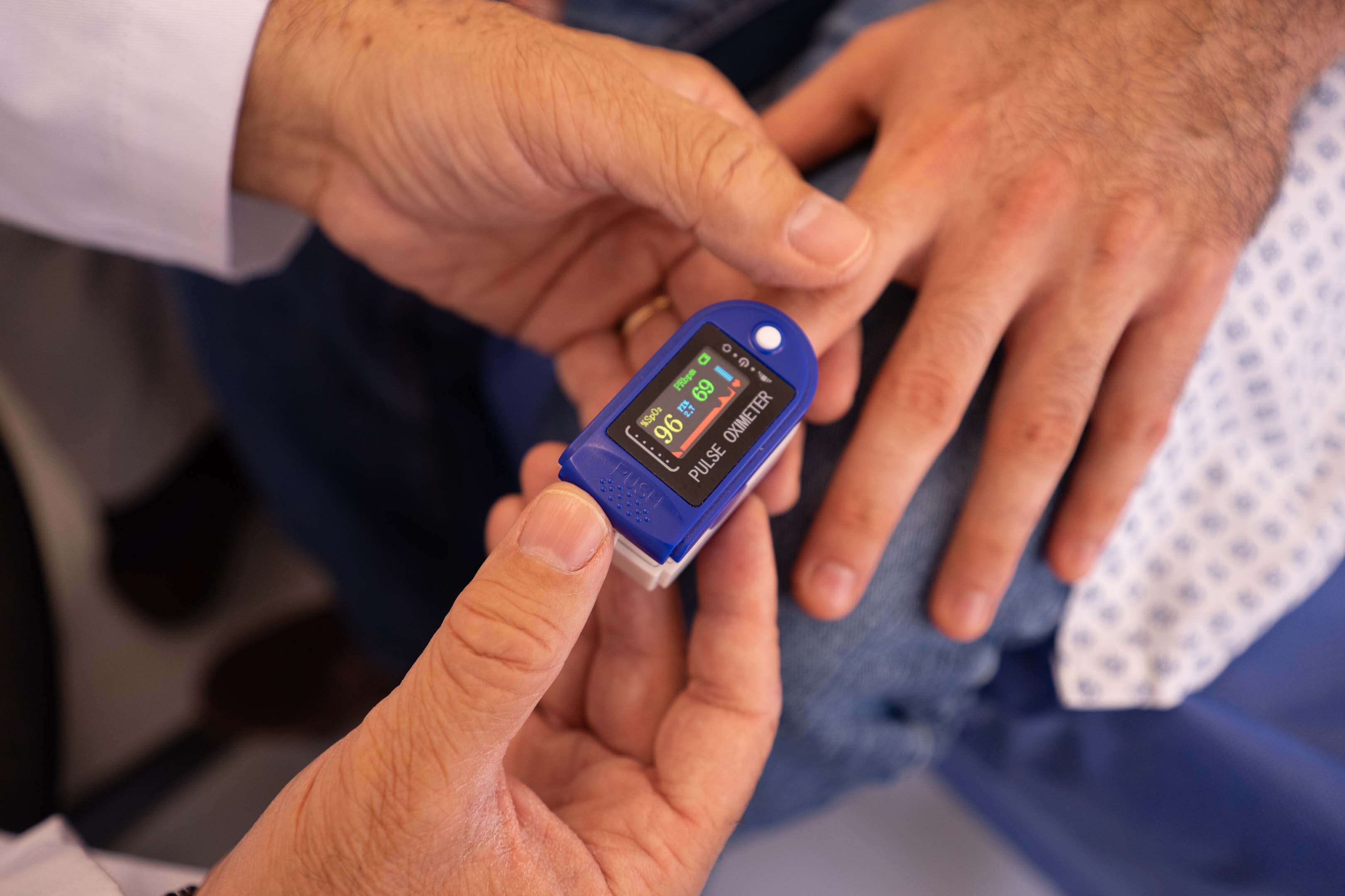 A doctor checking someone's blood pressure with a pulse ohmmeter.