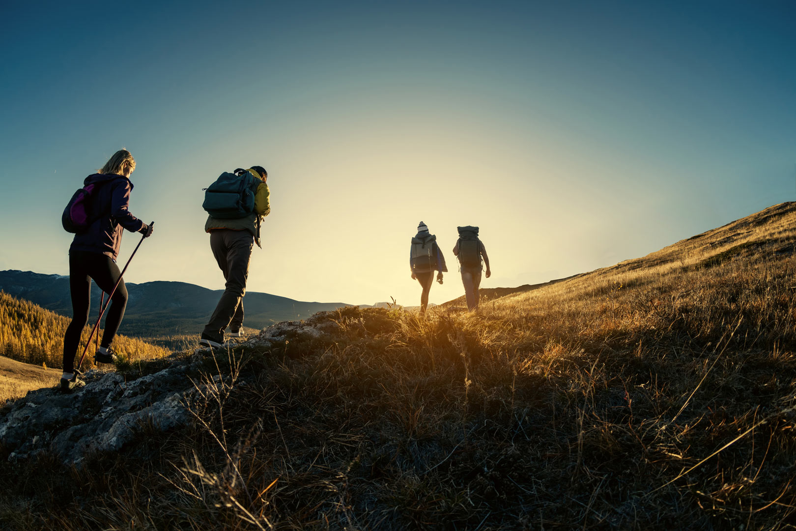Group of four hikers, walking up a mountain in England at sunset