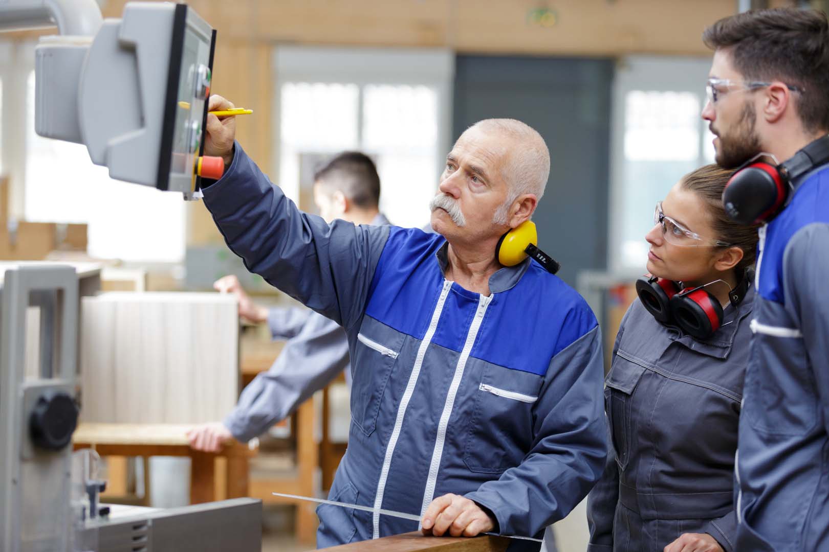 Engineer and apprentices working on machines in a factory