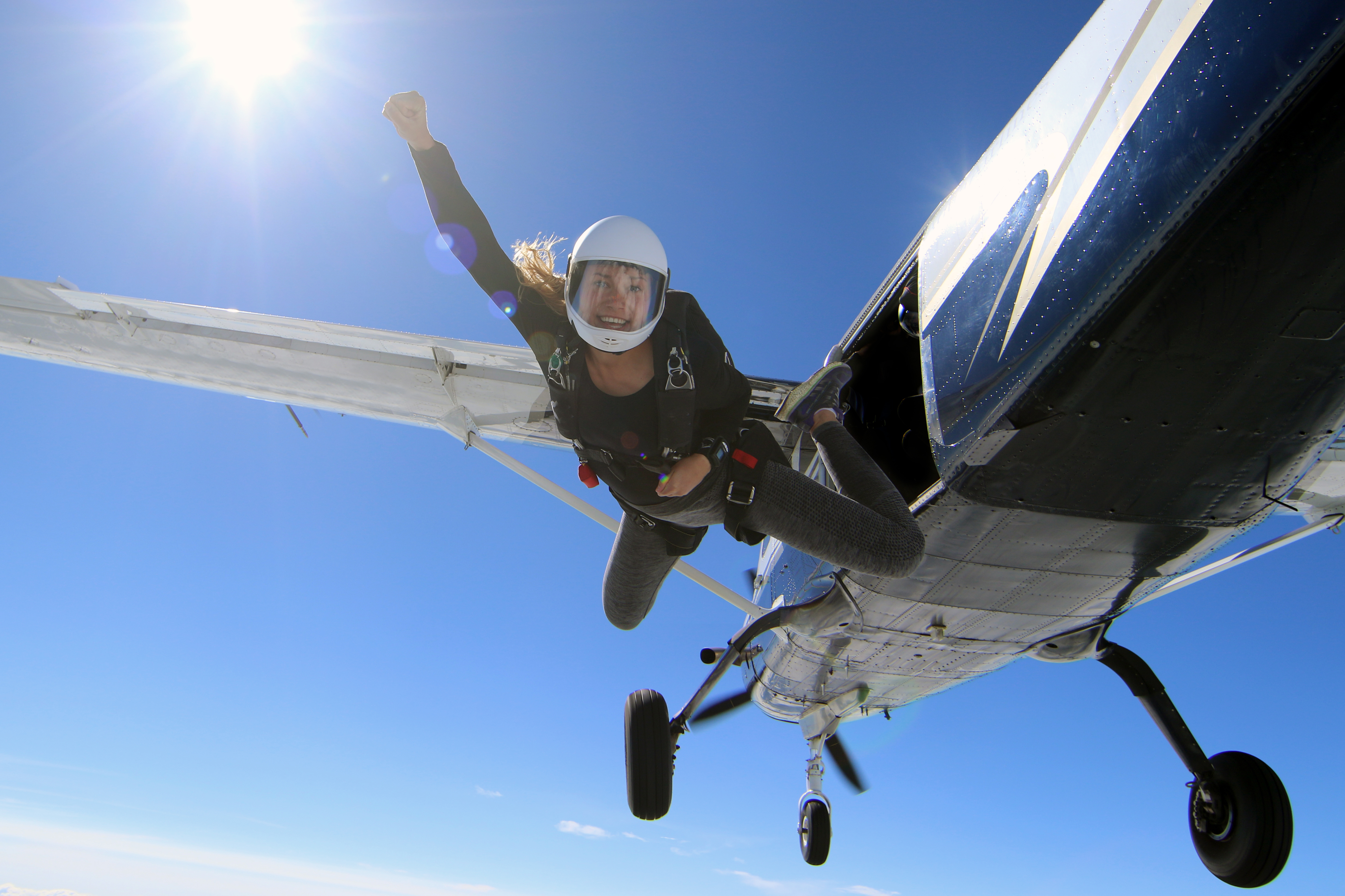 Female skydiver jumping out of a flying aeroplane in beautiful blue sky 