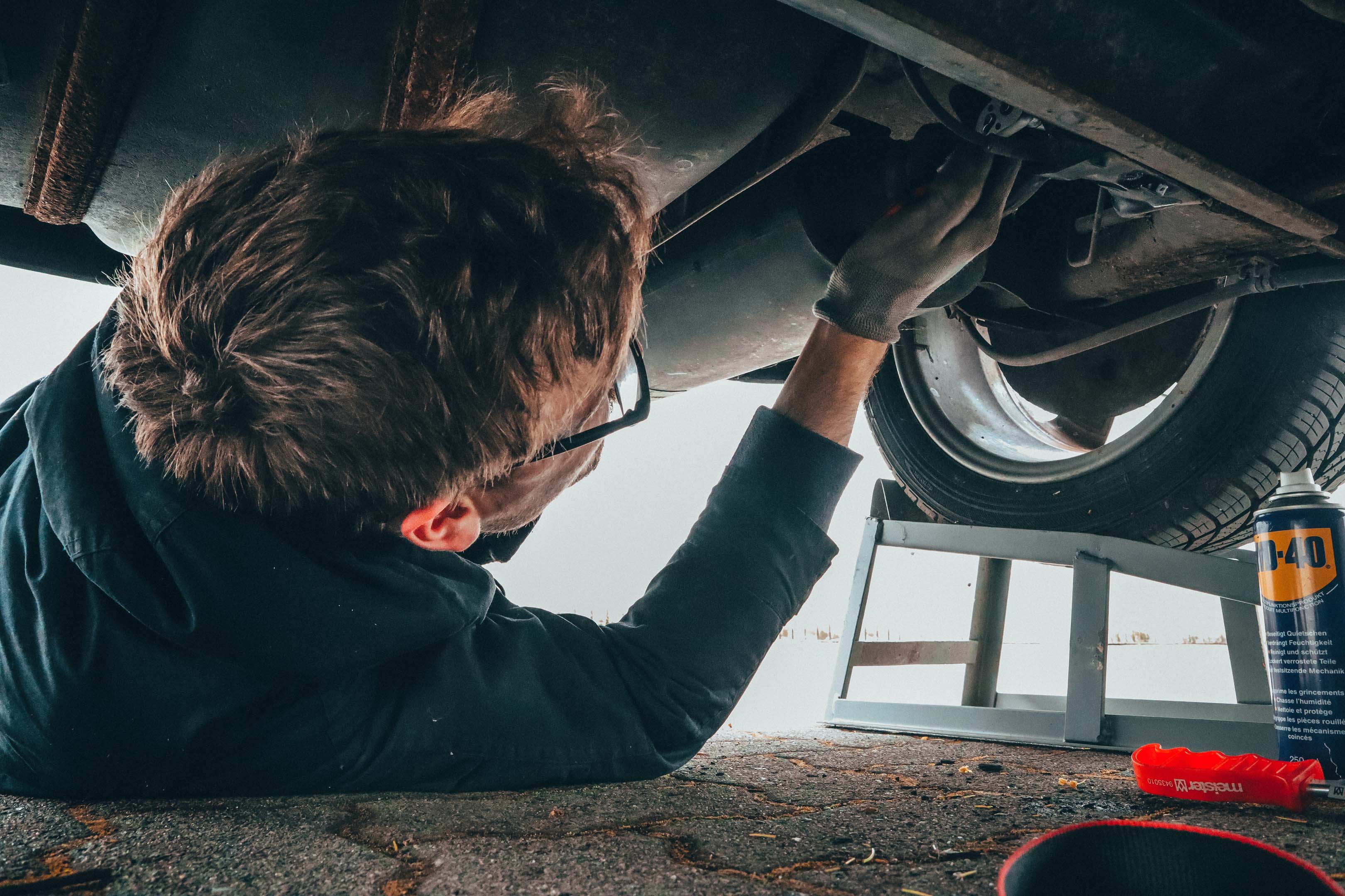 A mechanic (vehicle technician) lying on the floor working on the under side of a car