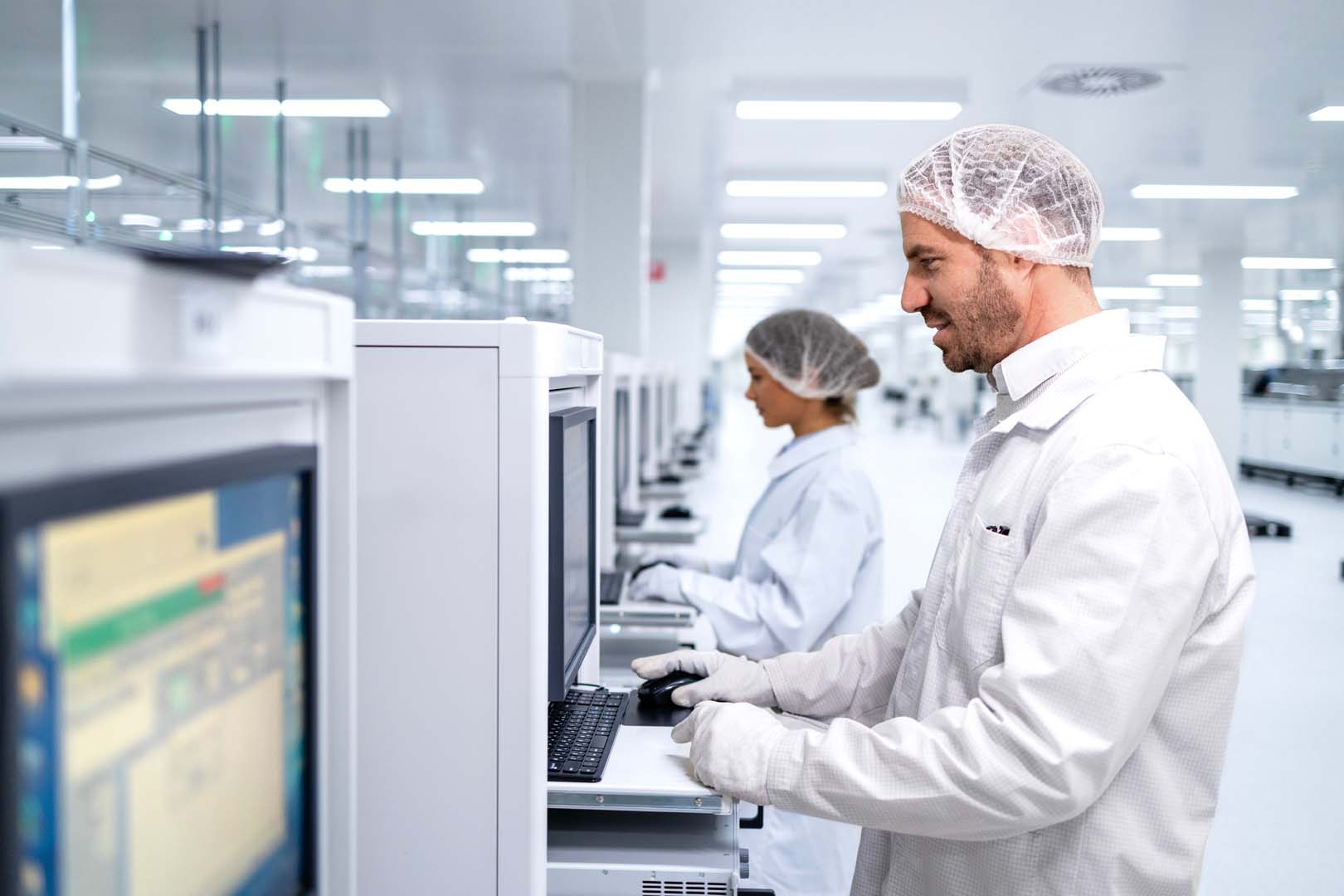 Employees working on machine computers at a factory assembly line.
