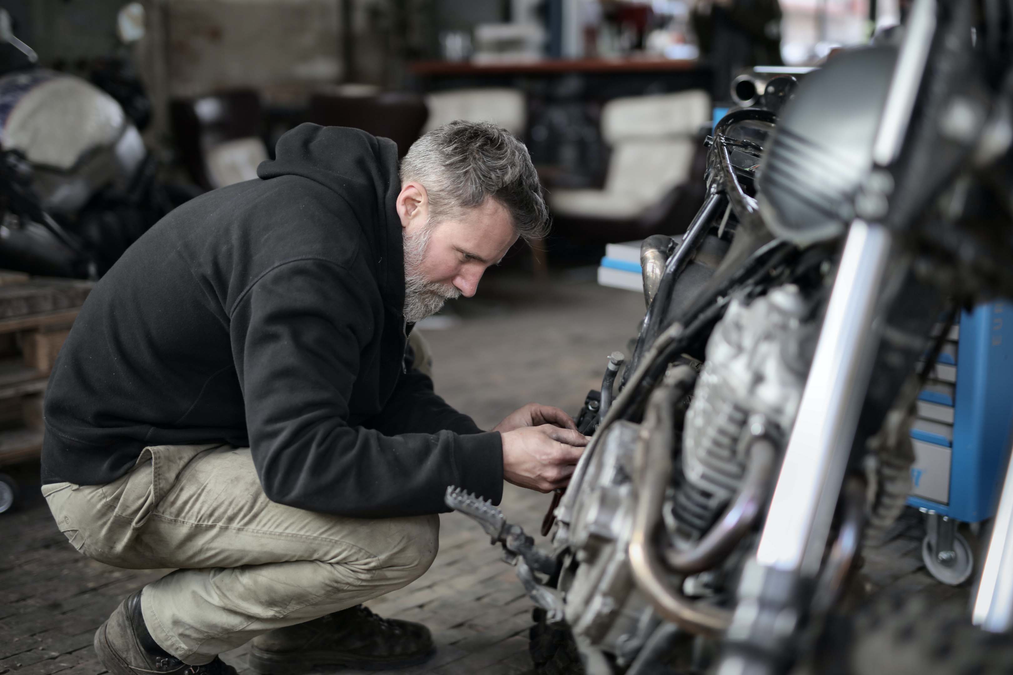 A mechanic working on a motorbike in a garage.