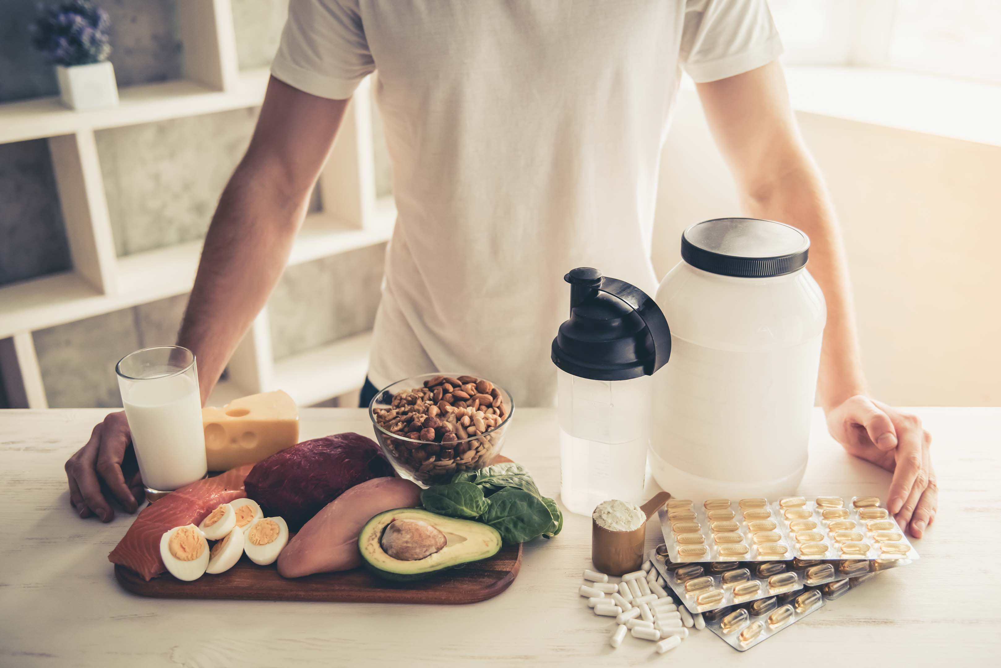 A person standing at a kitchen counter which has a variety of healthy nutritional foods on it to aid physical activity