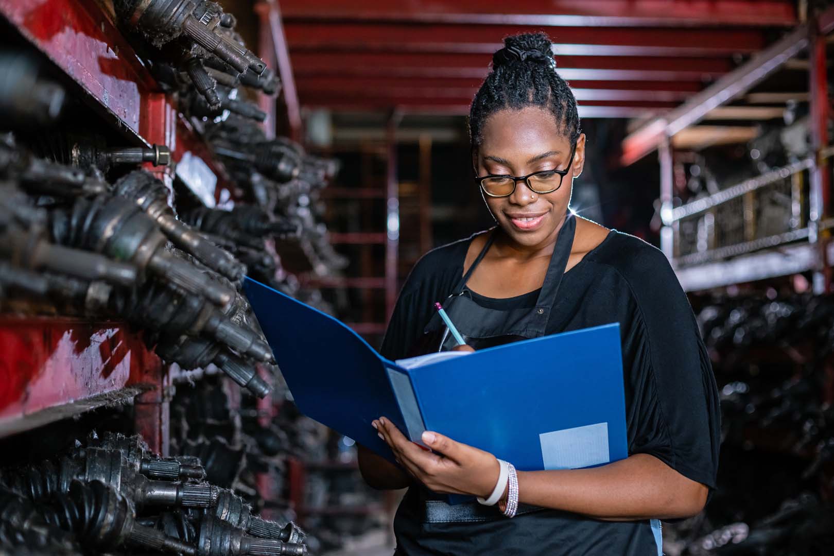 Woman holding a clipboard standing in auto parts factory