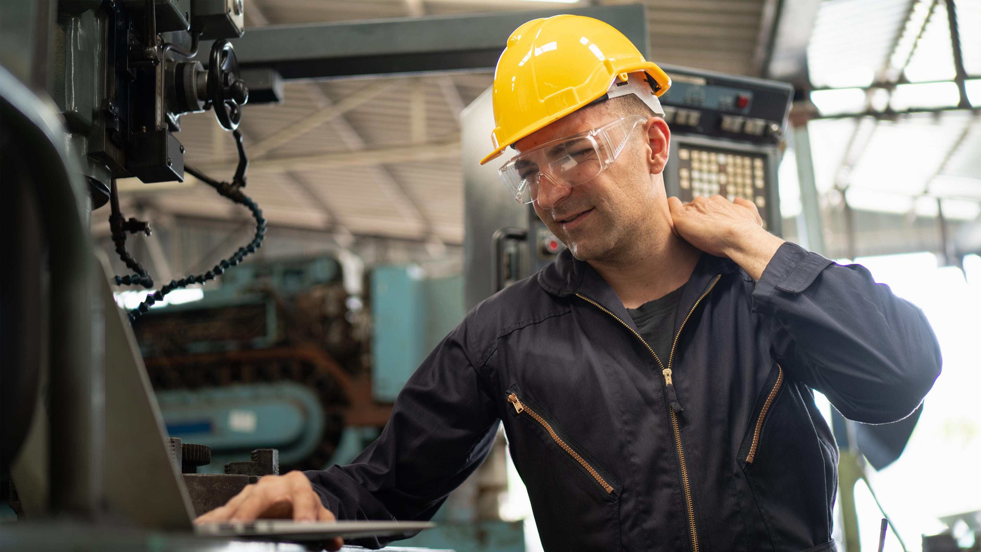 A person in a car manufacturing setting struggling with back pain.