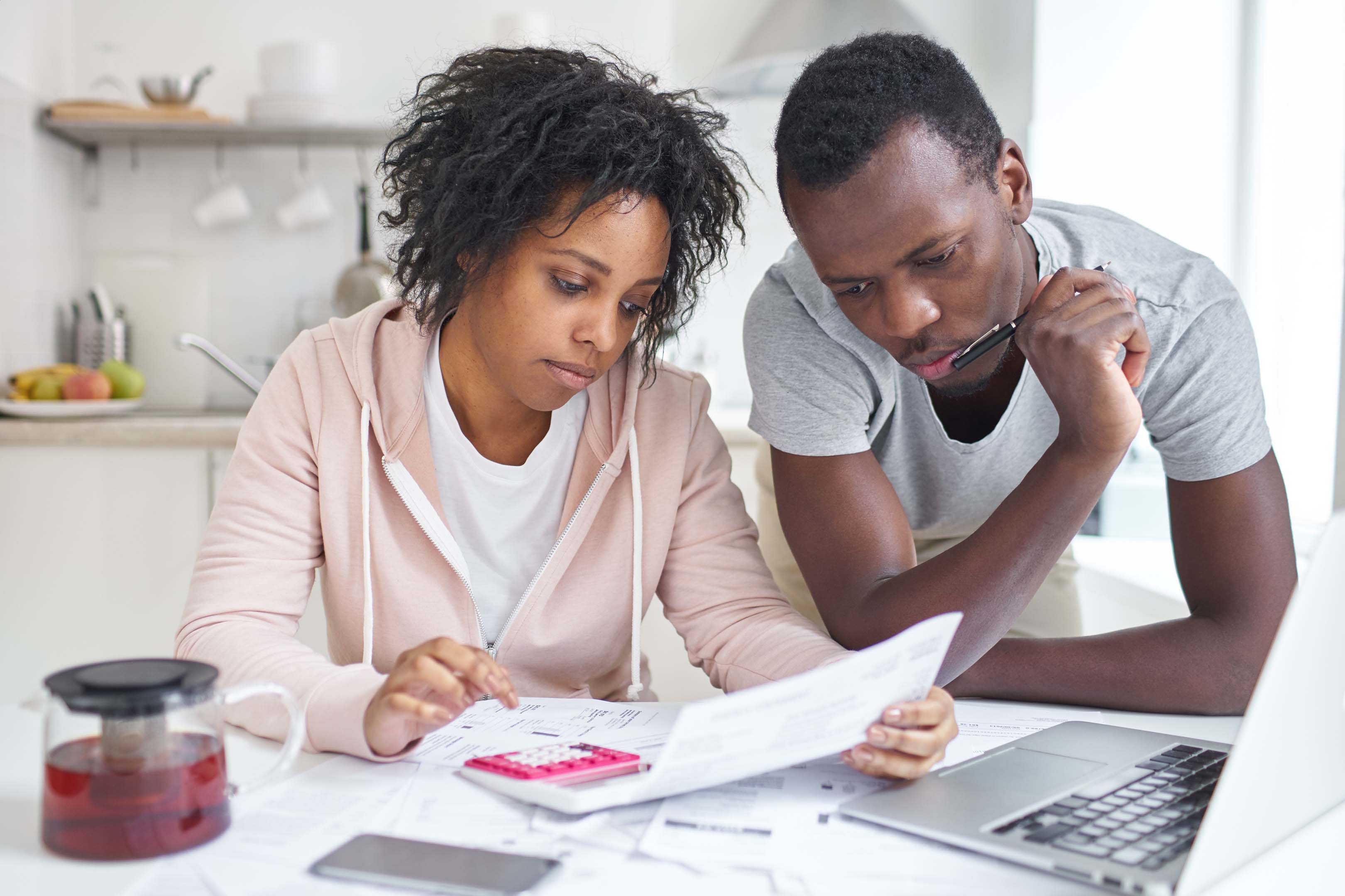 Two people planning their budget with paper, a calculator and laptop