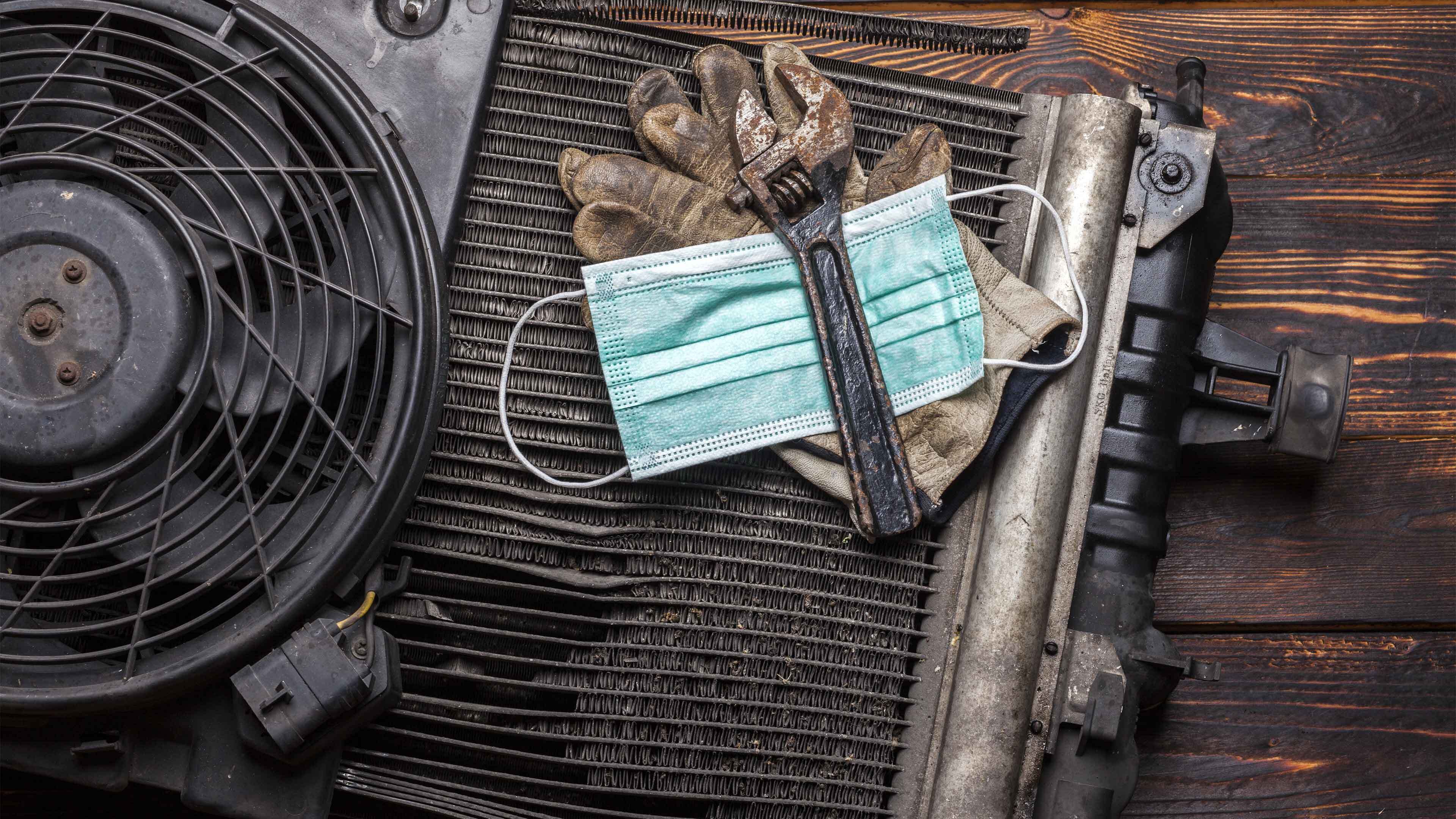 A face mask, spanner and gloves in a pile on a work bench