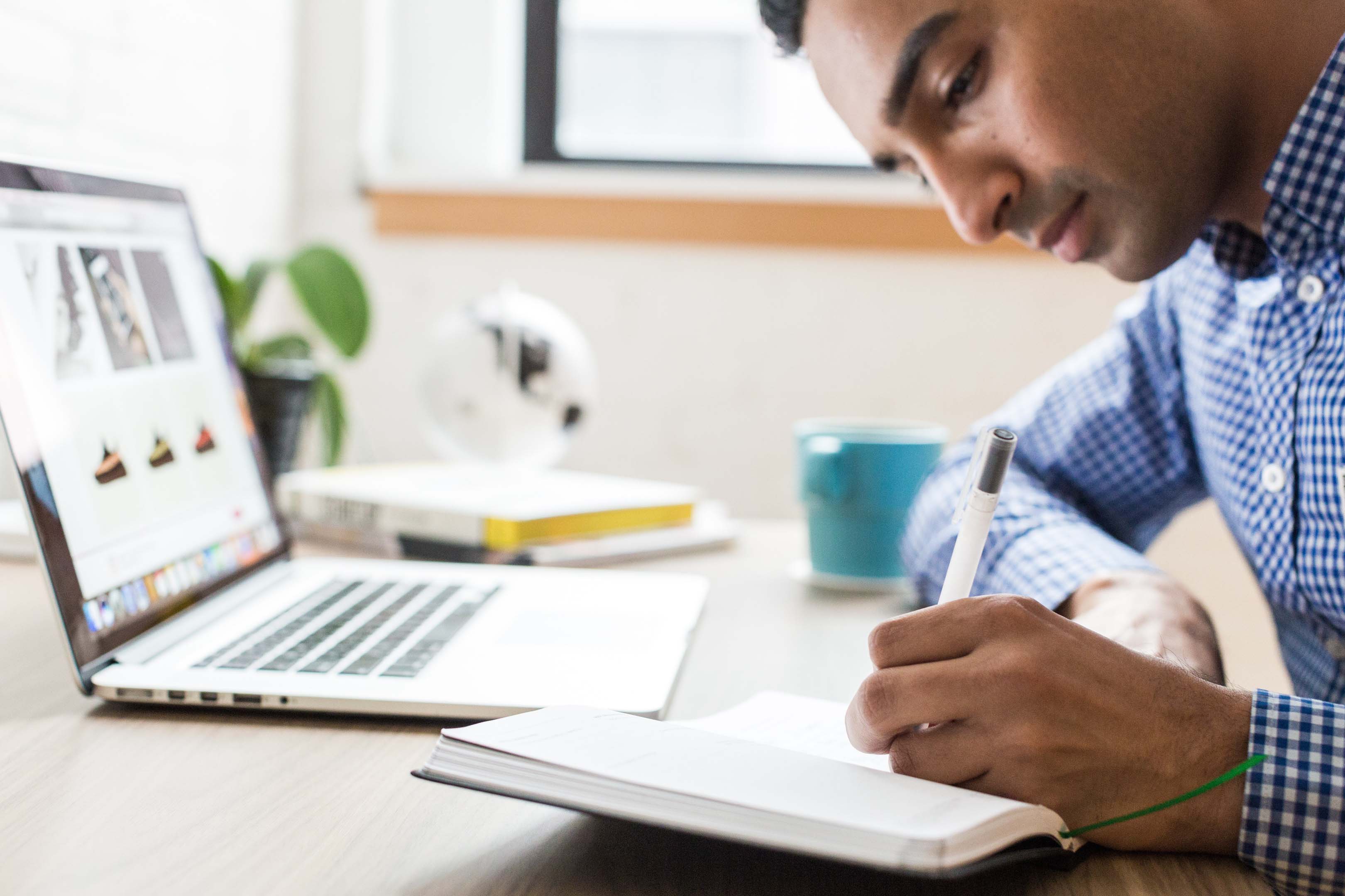Man preparing for typical interview questions by researching information on the internet and making notes