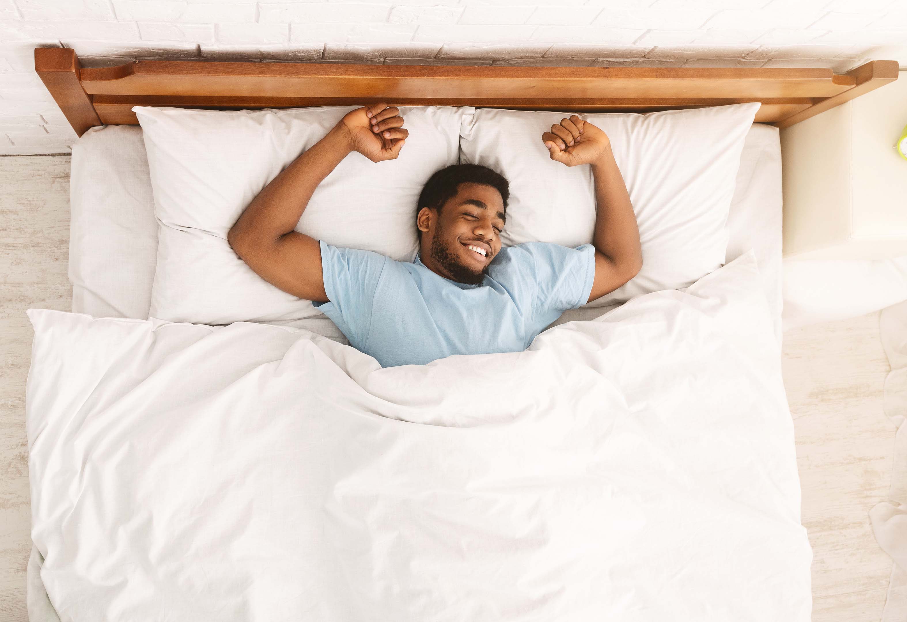 Person happy and lying in bed after a good sleep. Using tips to improve sleep. Longer, restful and deeper sleep. 