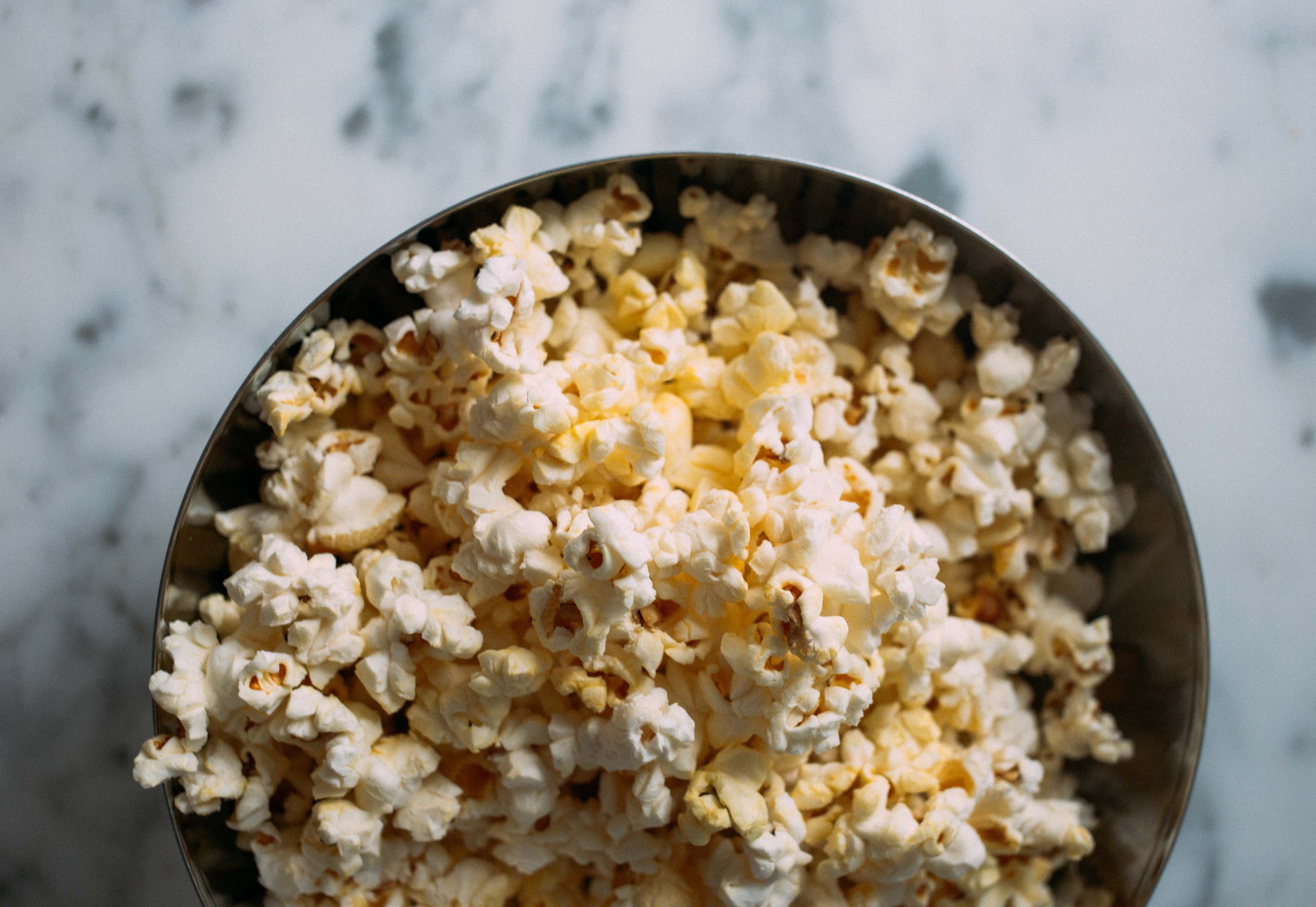 A large bowl of popcorn sitting on a table for a healthy snack
