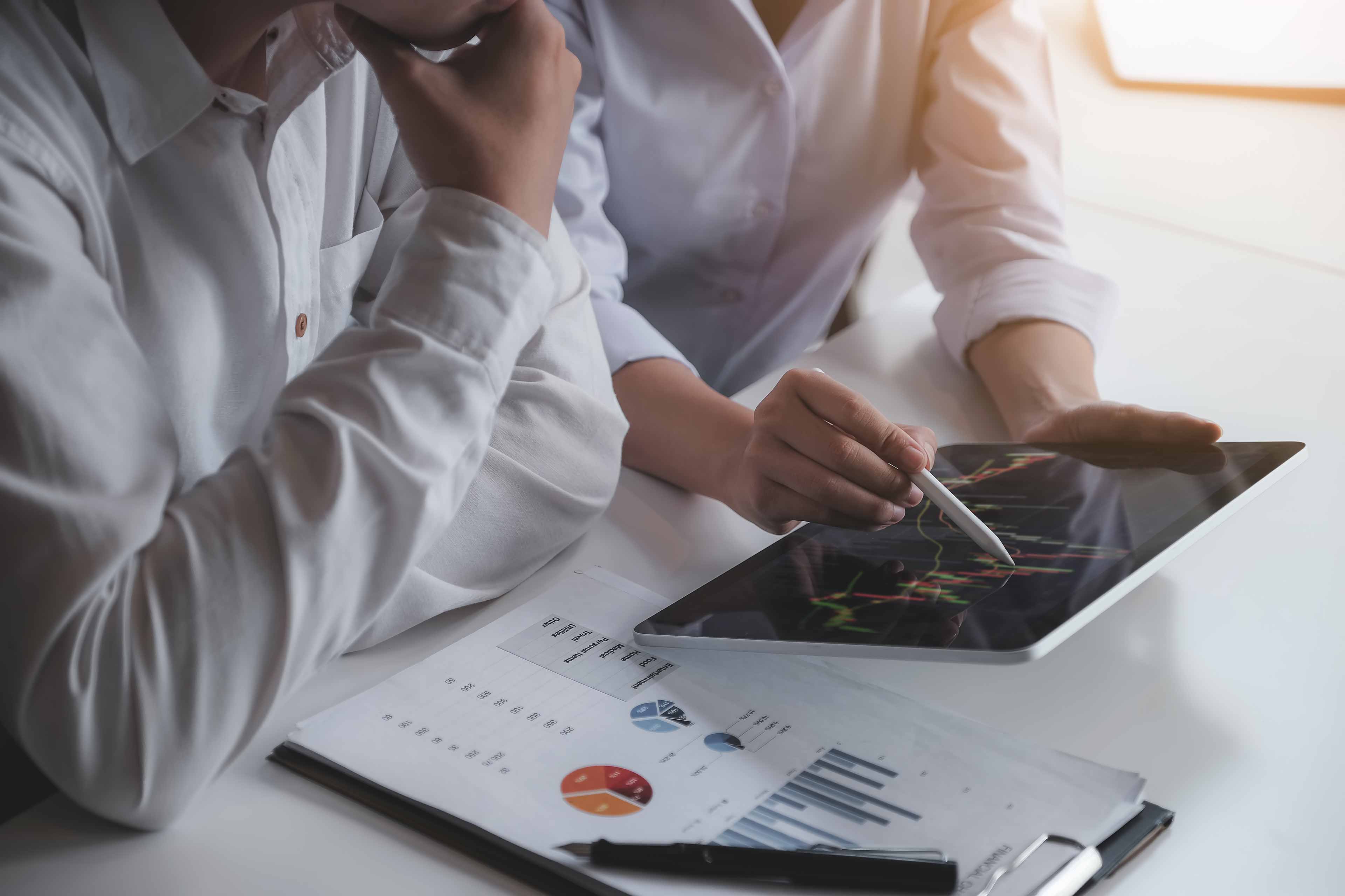 Two people reviewing figures on a tablet