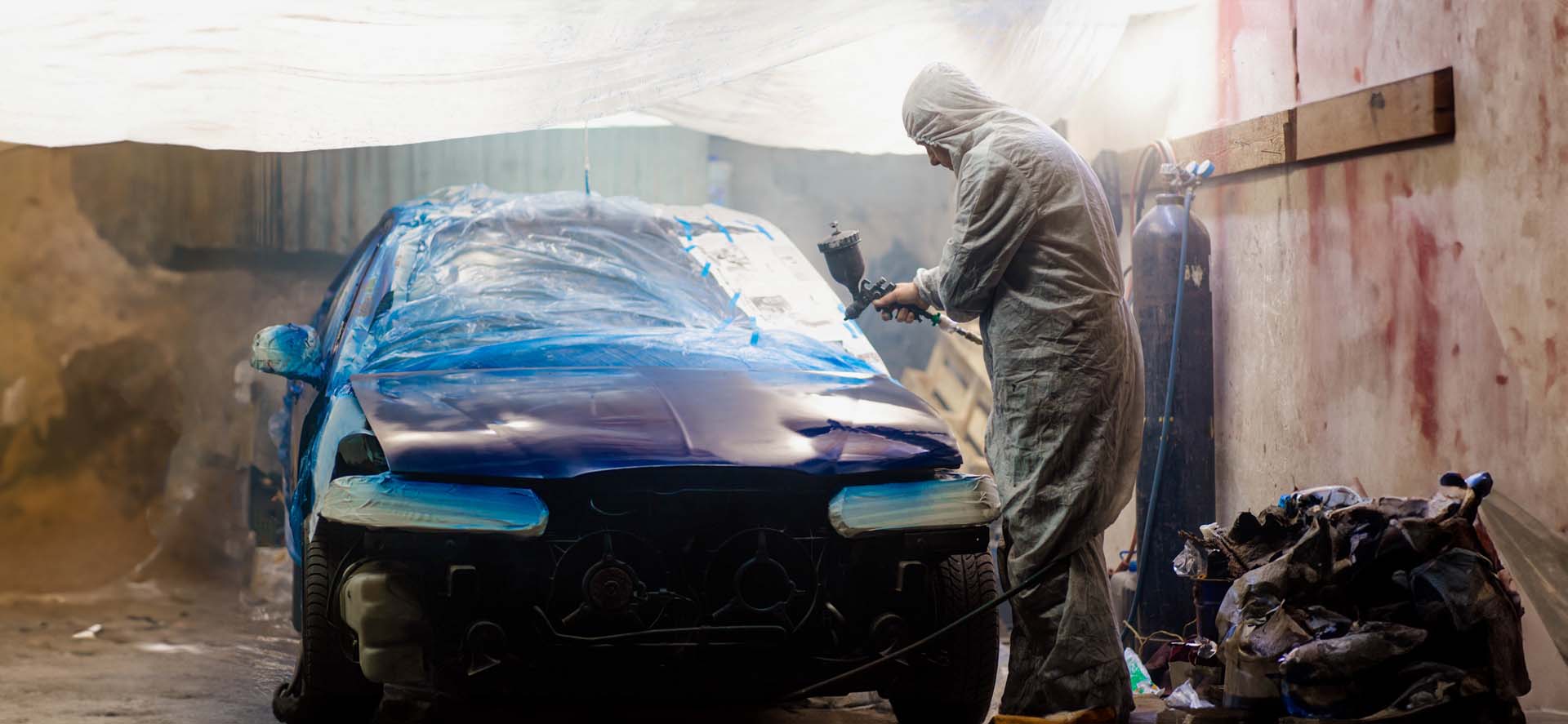 Car painter paints a car with a spray gun. Car painting at home.